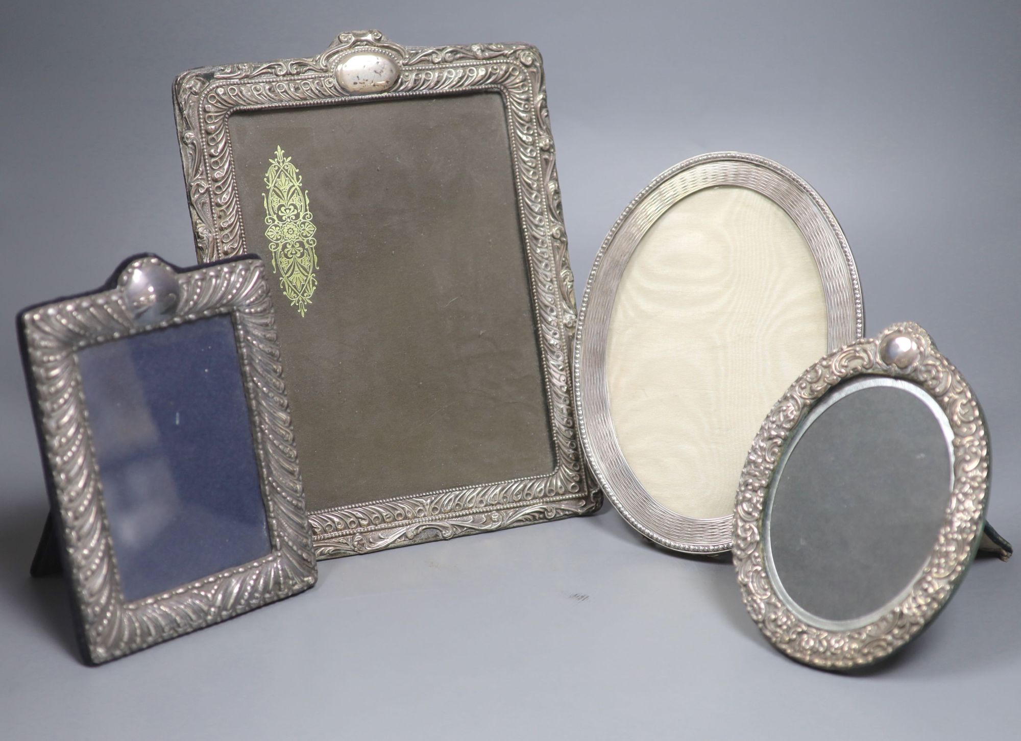 A George V oval silver photograph frame with reeded and beaded border, London 1910, 21.5cm and three other silver frames.